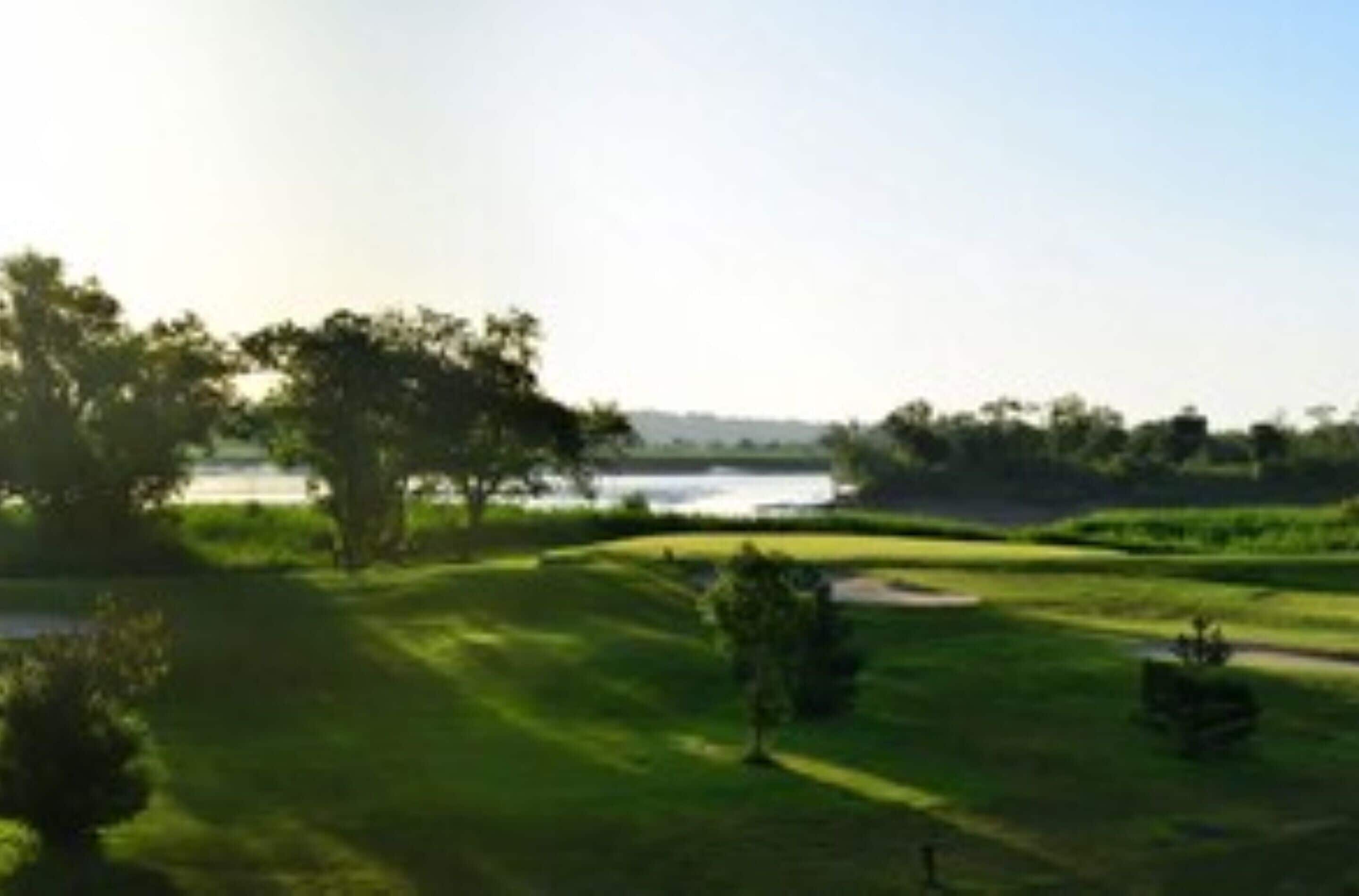 A golf course with a water body in the background.