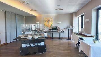 A modern dining area with a buffet setup, a large abstract painting on the wall, and a window providing natural light.