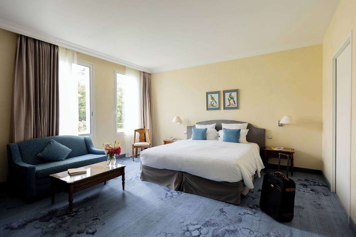 Une chambre d’hôtel avec un lit, un canapé, une table basse et un bureau.