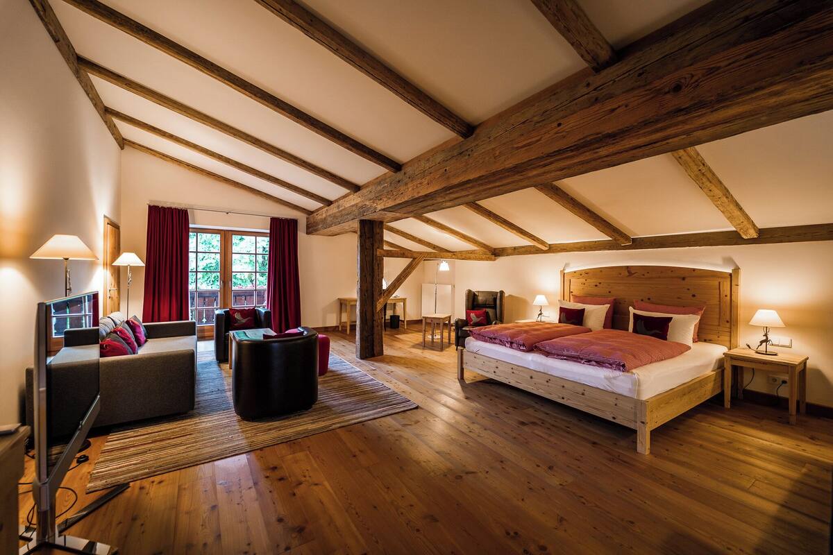 A room with a bed, a sofa, a desk, and a TV.
