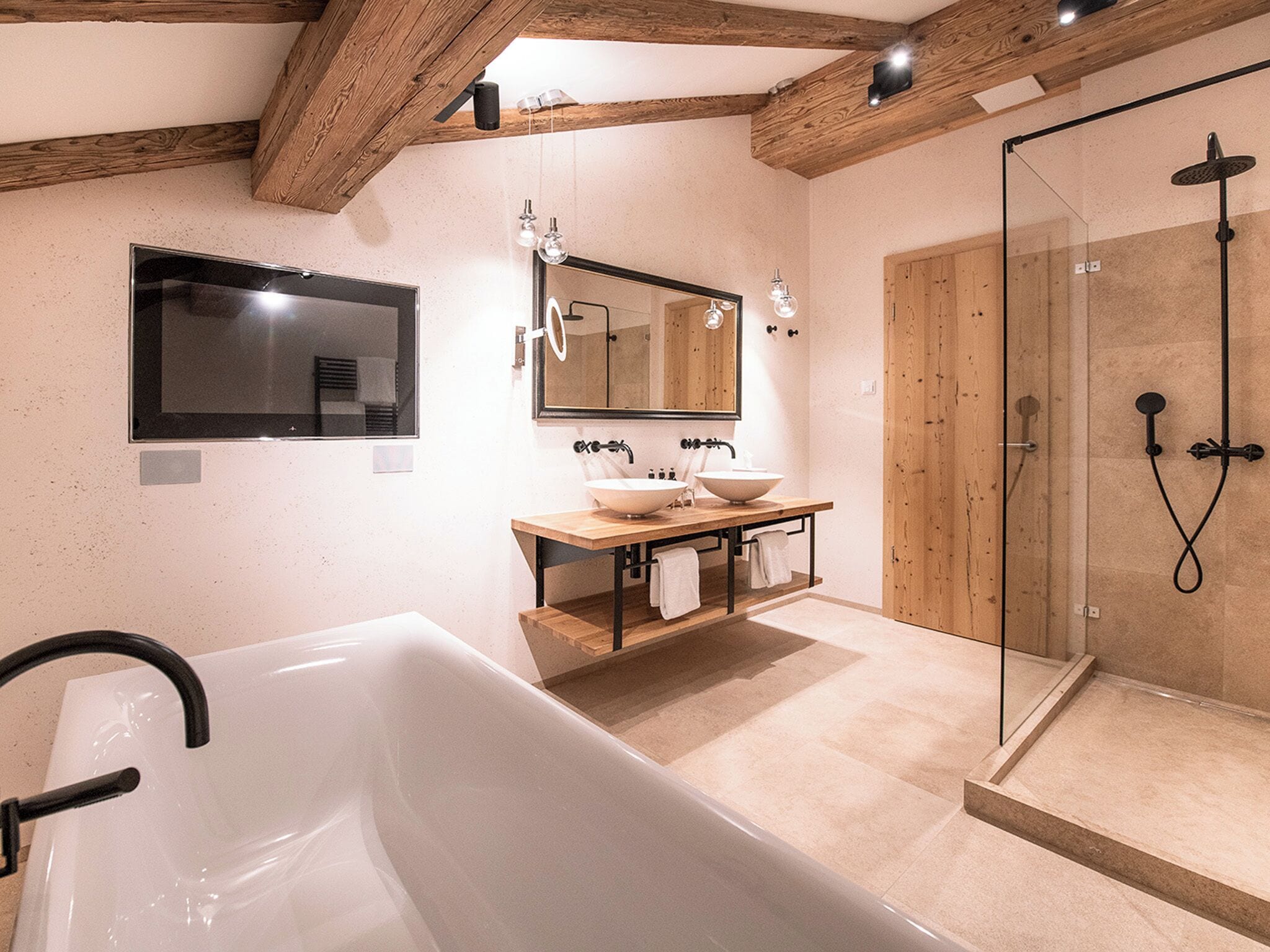 A modern bathroom with a freestanding bathtub, a double sink vanity, a large mirror, and a glass-enclosed shower area.