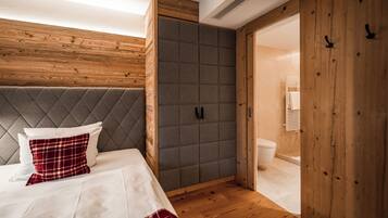 Un dormitorio con una cama, un armario tapizado en gris, paredes de madera y suelo de madera.