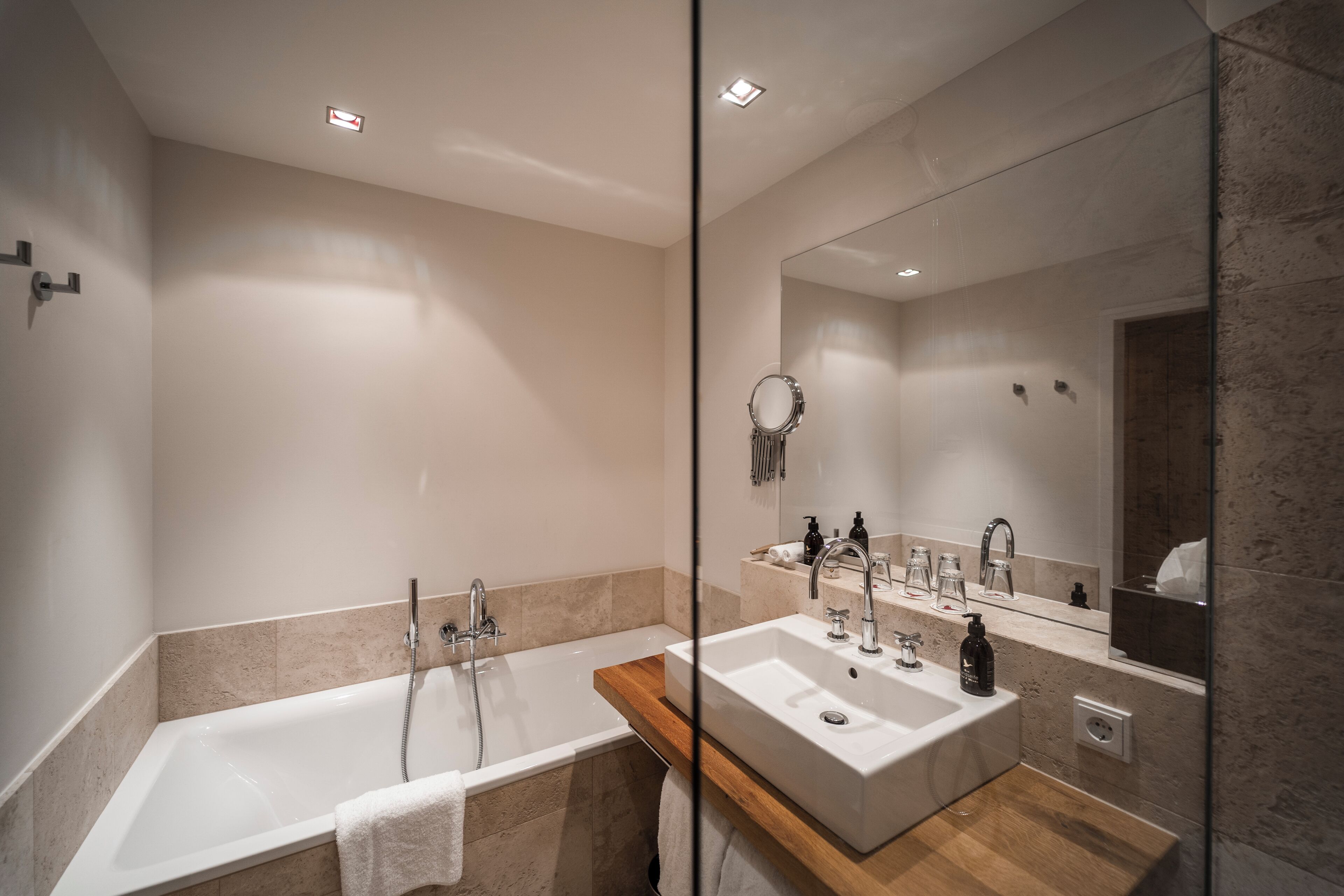 A modern bathroom with a bathtub, a sink, and a large mirror.