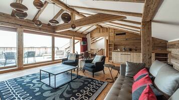 Ein großzügiger Wohnbereich mit einer Couch, Sesseln, einem Couchtisch und einem gemusterten Teppich.
