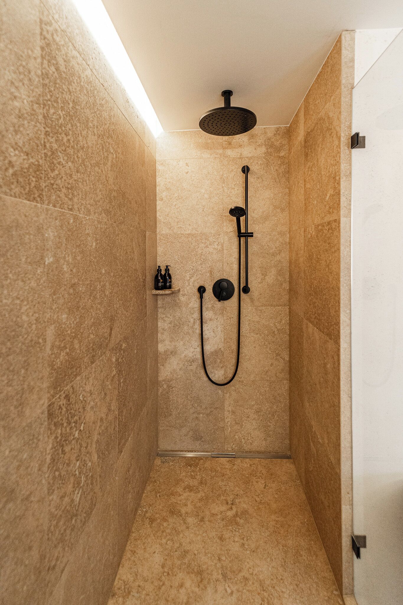 Un espacio de ducha pequeño y cerrado con una ducha de mano y un grifo instalado en la pared.