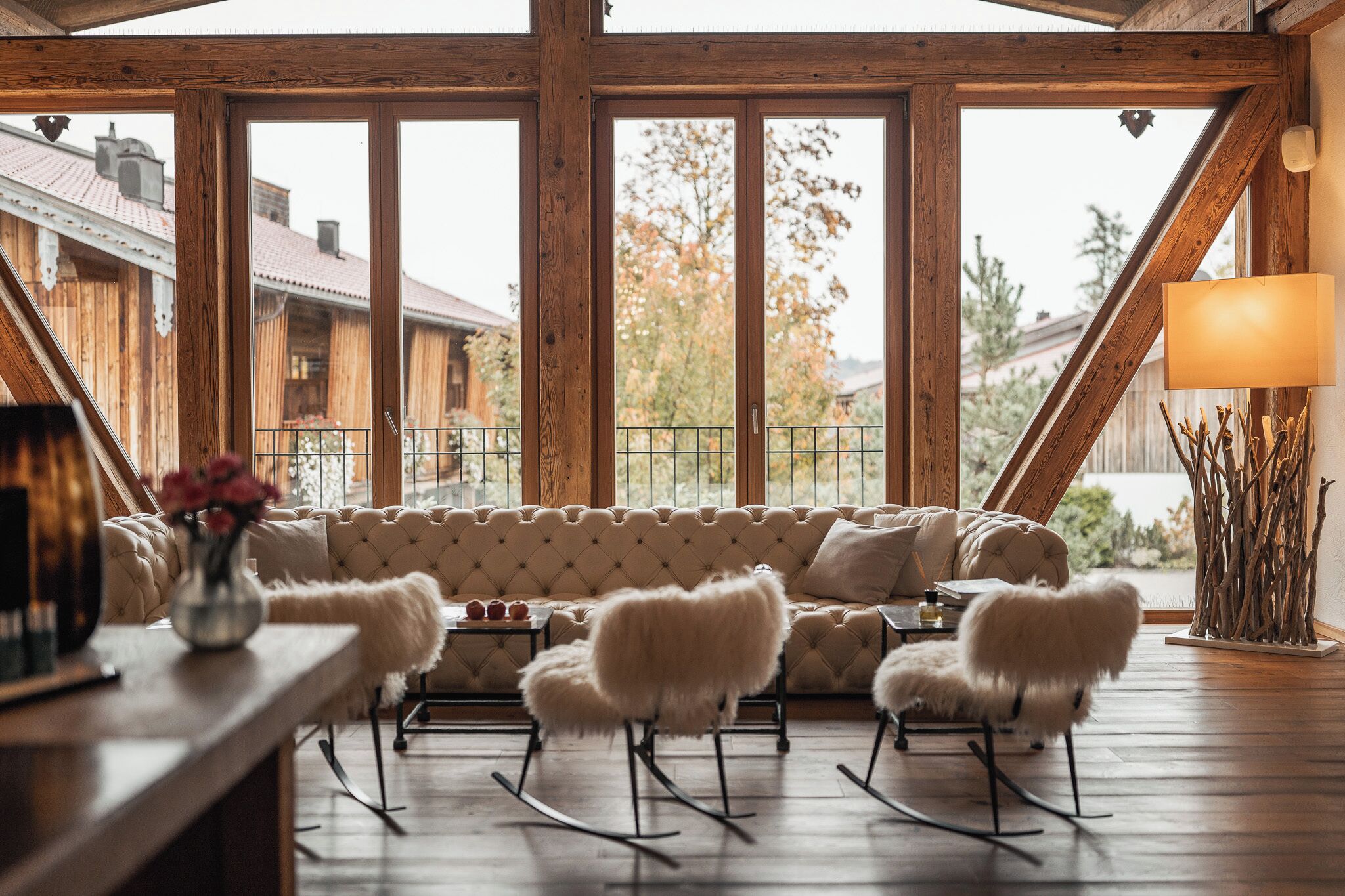 A wooden interior with a sofa, rocking chairs, a table, and a lamp.