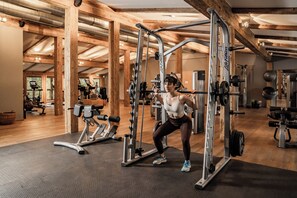 A gym with wooden beams, exercise equipment, and a treadmill.