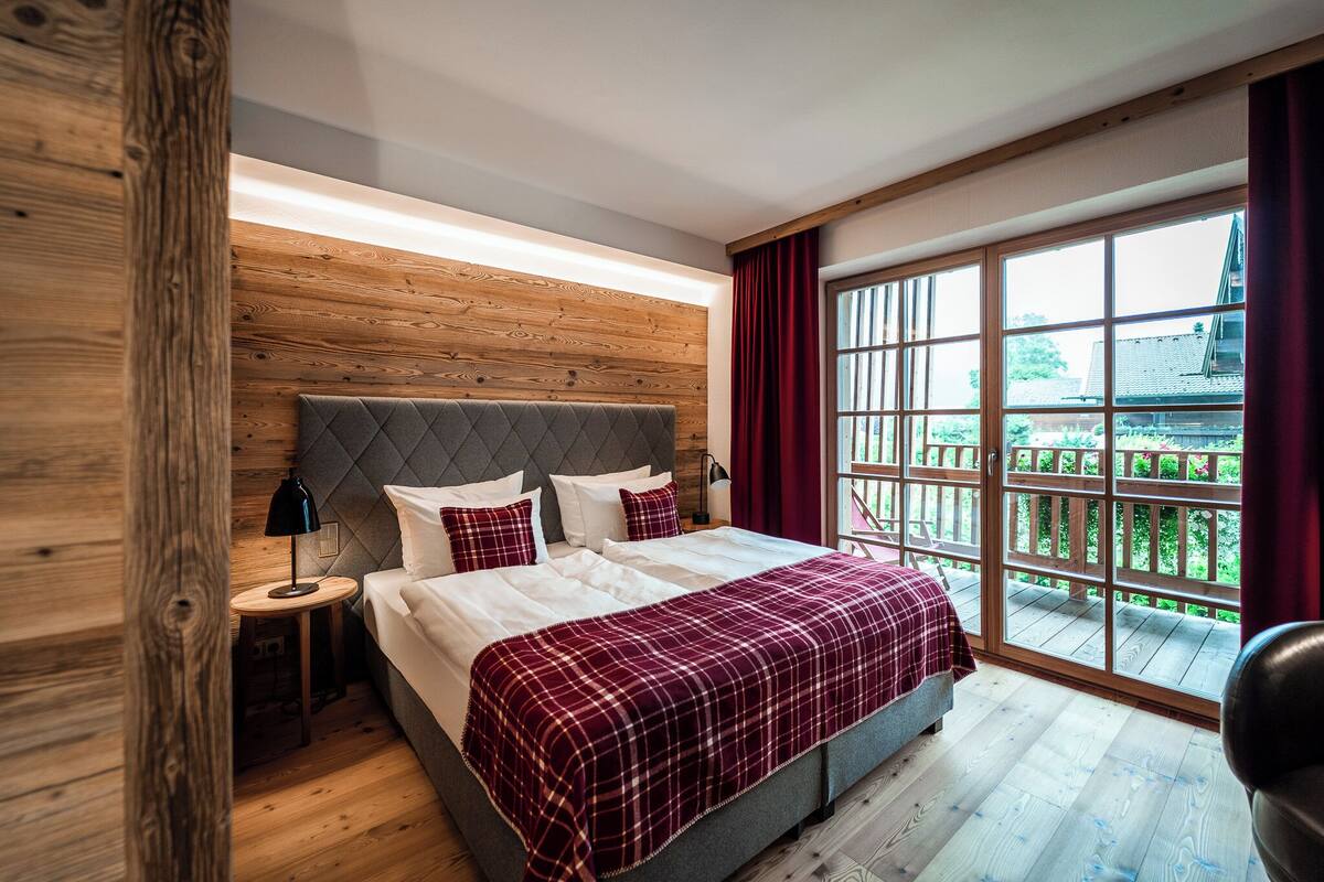 A bedroom with a bed, nightstand, and a view of a balcony.