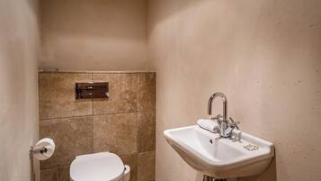 Une salle de bain avec des toilettes, un lavabo et une poubelle.