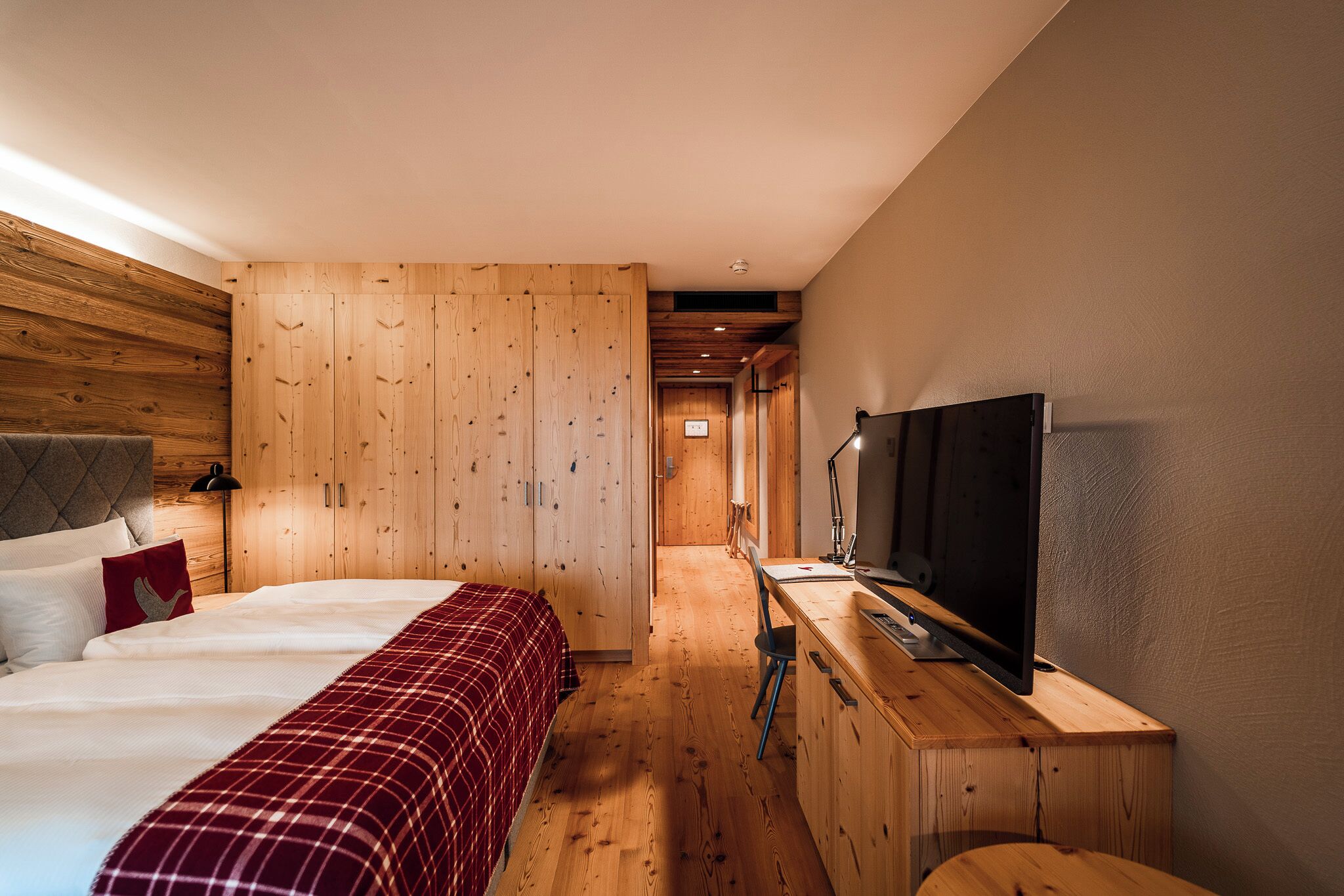 Un dormitorio con cama, televisión, escritorio y armario.