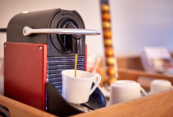 Una máquina de café Nespresso sirviendo café en una taza blanca.