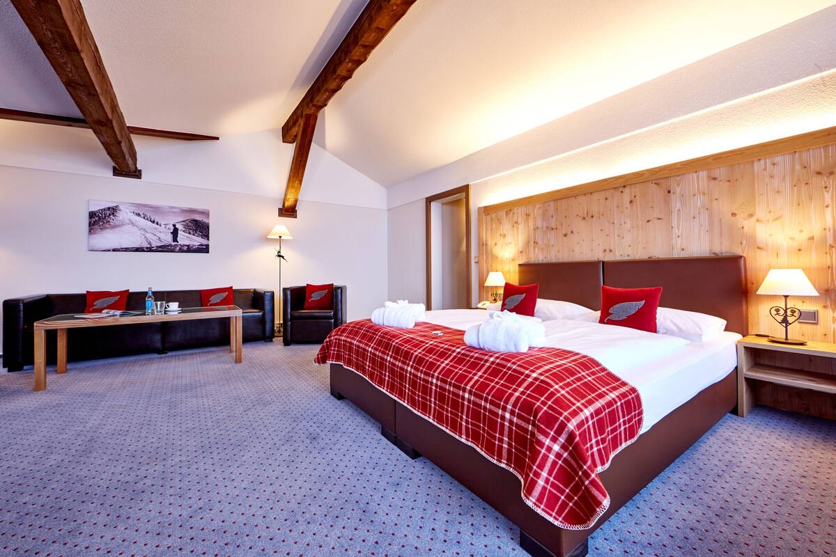 Een hotelkamer met een groot bed, een houten hoofdbord, een bureau en een stoel.