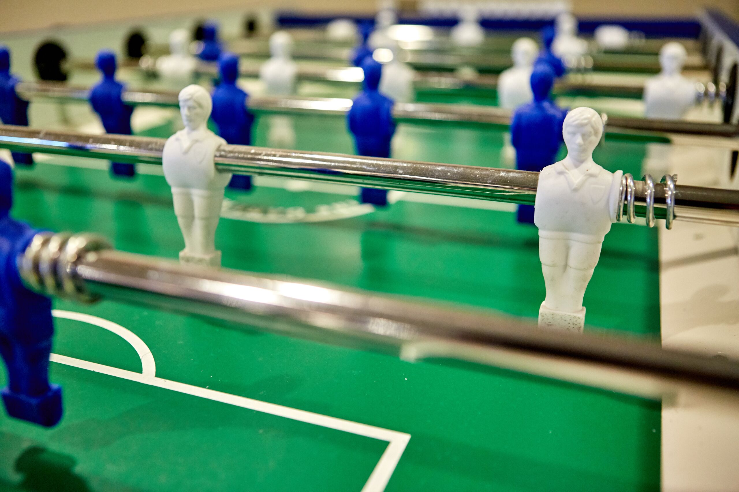 A close-up of a foosball table with white and blue player figures.