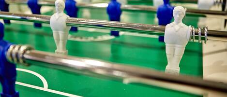 A close-up of a foosball table with white and blue player figures.