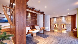 Un interior moderno con una escalera de madera, dos sillas colgantes, un muro de piedra y un banco de madera.
