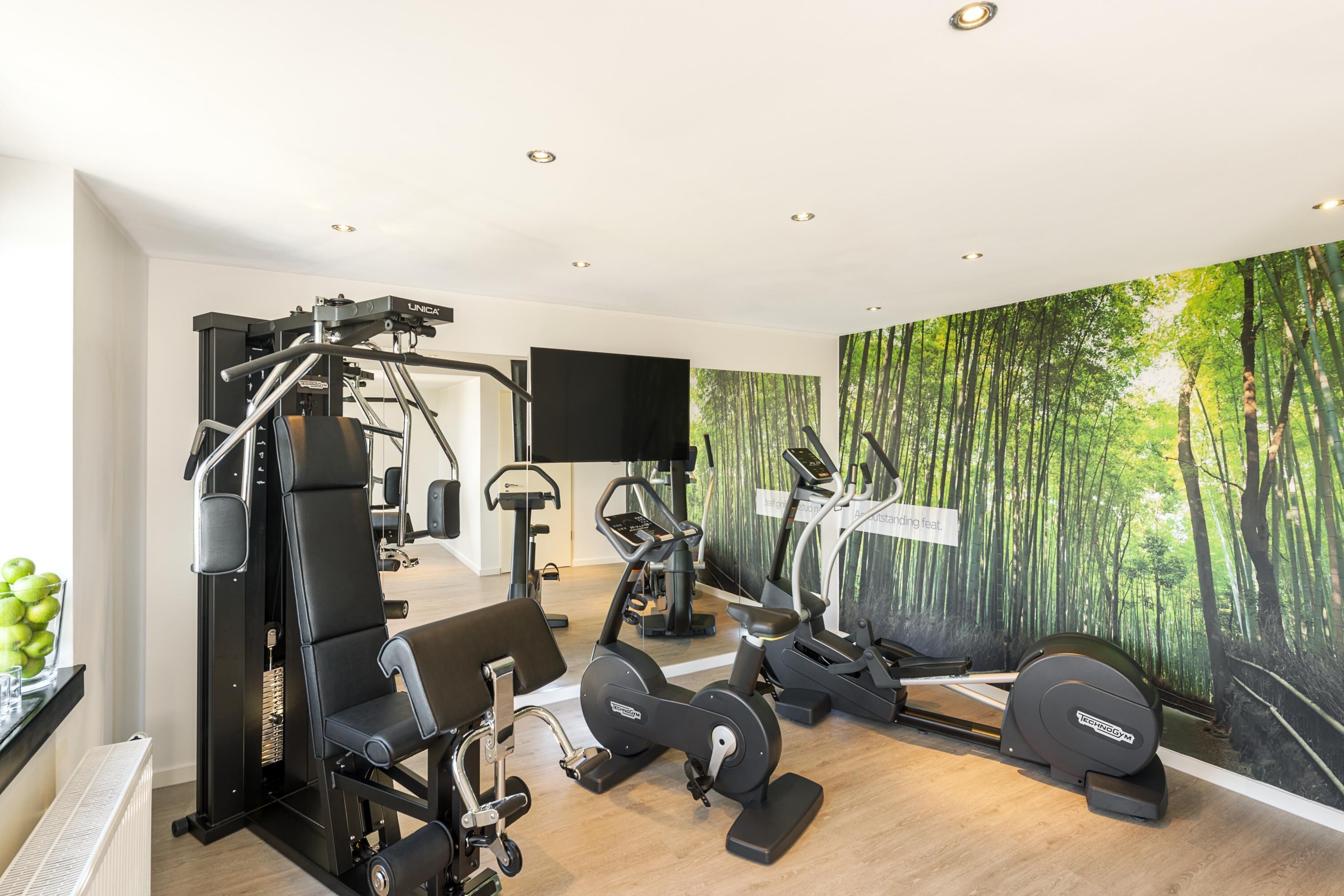 A modern gym with various exercise equipment, including a weight machine, treadmills, and stationary bikes.