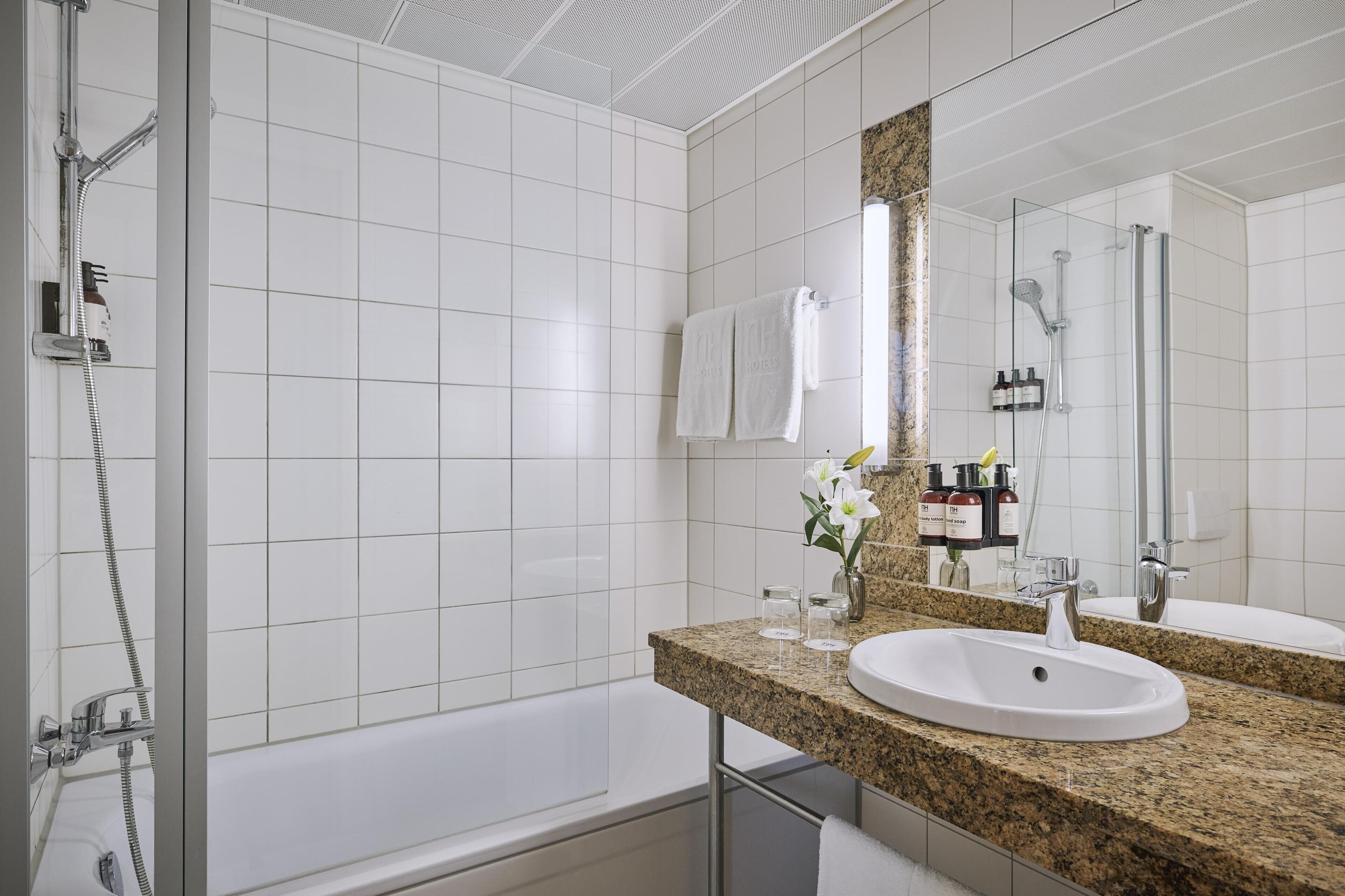 A modern bathroom with a shower, a bathtub, a sink, and a large mirror.