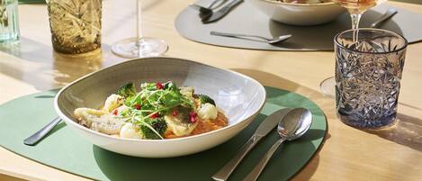 A dining table with a bowl of food, two glasses of wine, and a decorative glass.