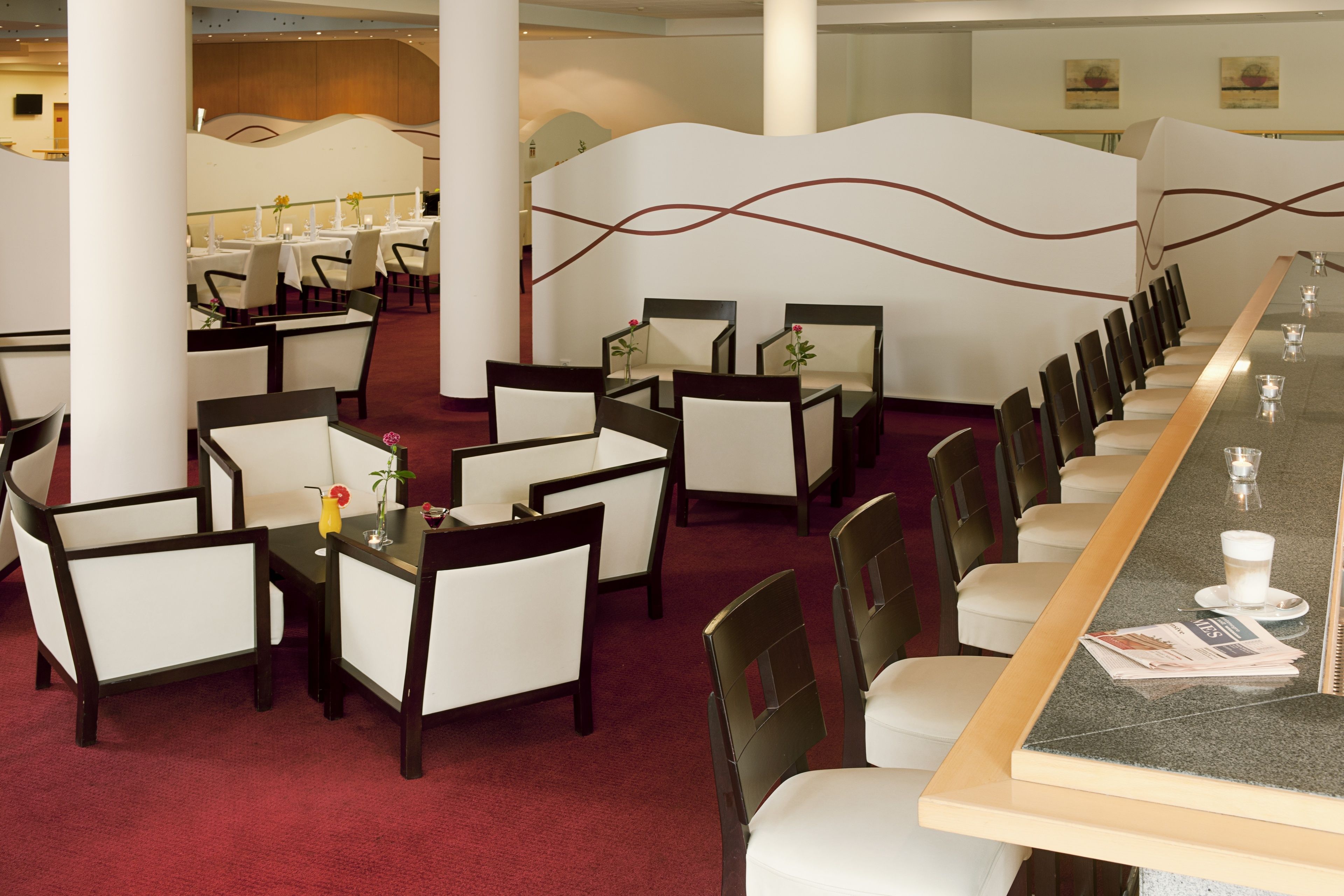 A restaurant with a long counter, multiple tables, and chairs.