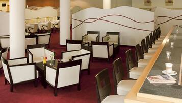 A restaurant with a long counter, multiple tables, and chairs.