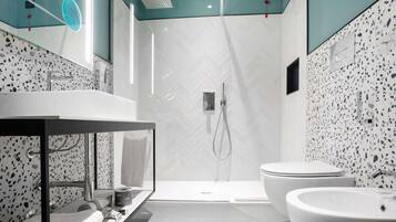 Un baño moderno con un espejo grande, un lavamanos y una ducha.