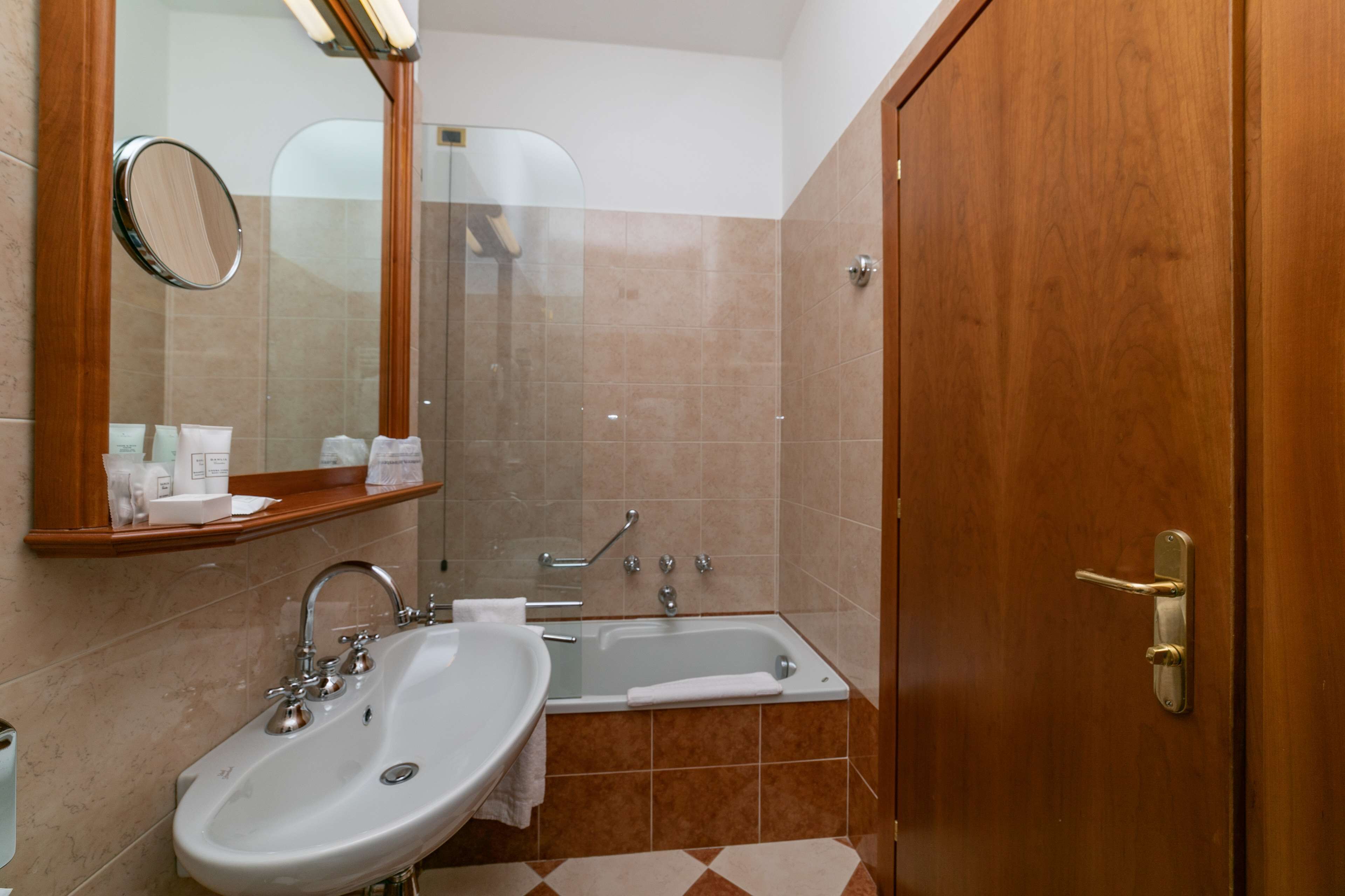 A bathroom with a sink, mirror, and bathtub.