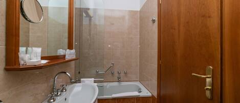 A bathroom with a sink, mirror, and bathtub.