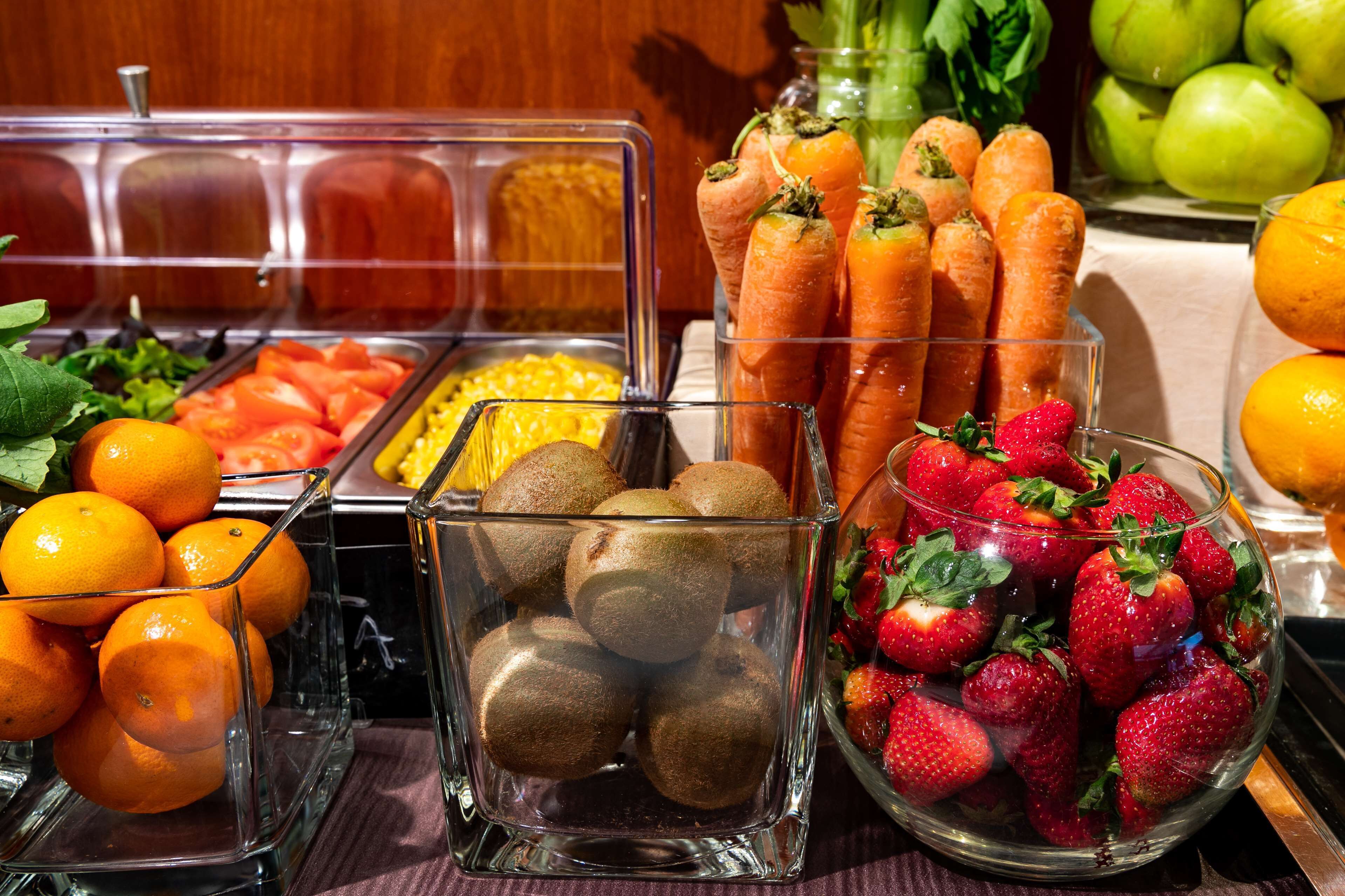 A buffet with various fruits and vegetables, including oranges, kiwis, carrots, and strawberries.