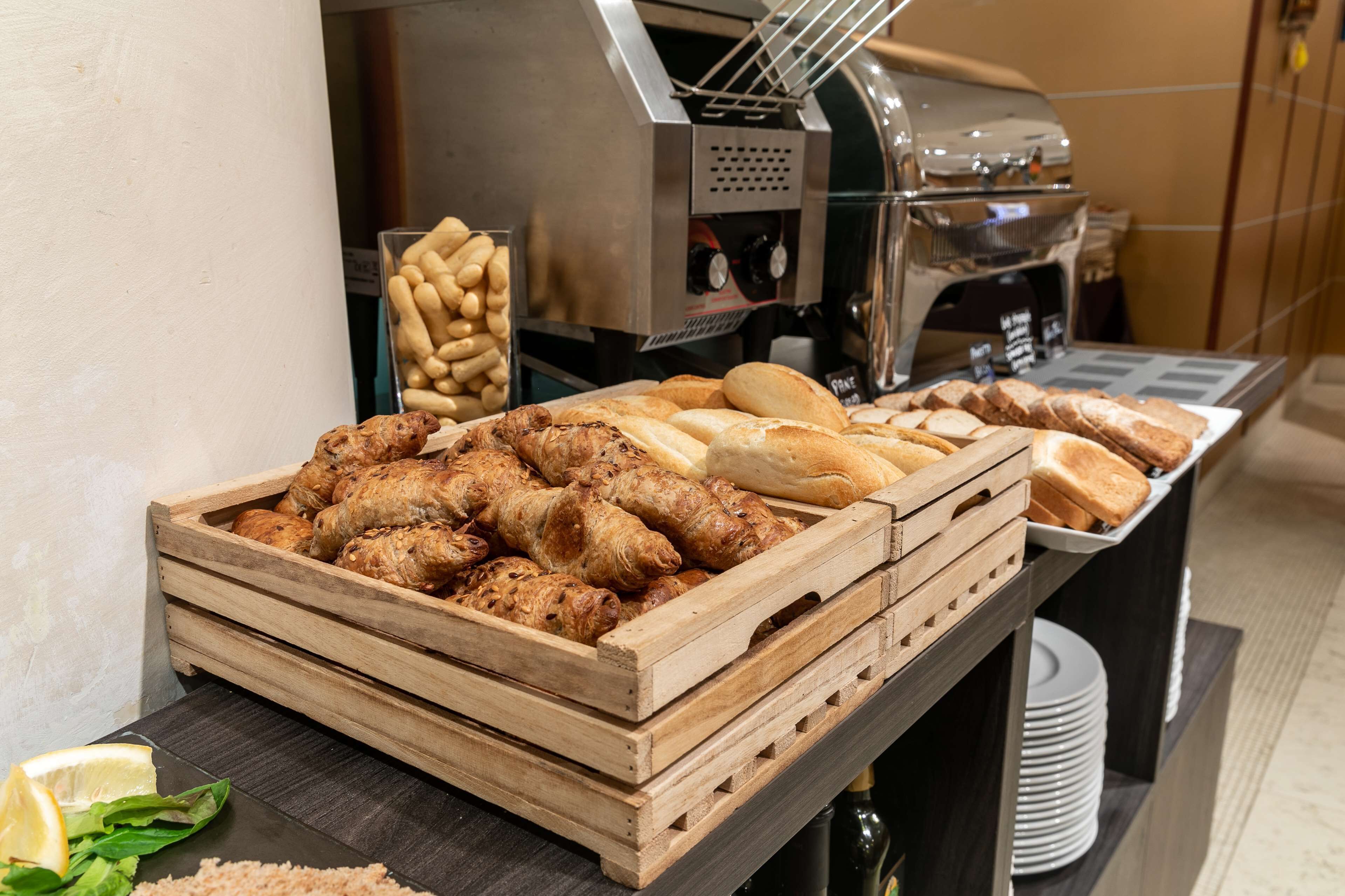 A buffet with various food items including pastries, bread, and a coffee machine.