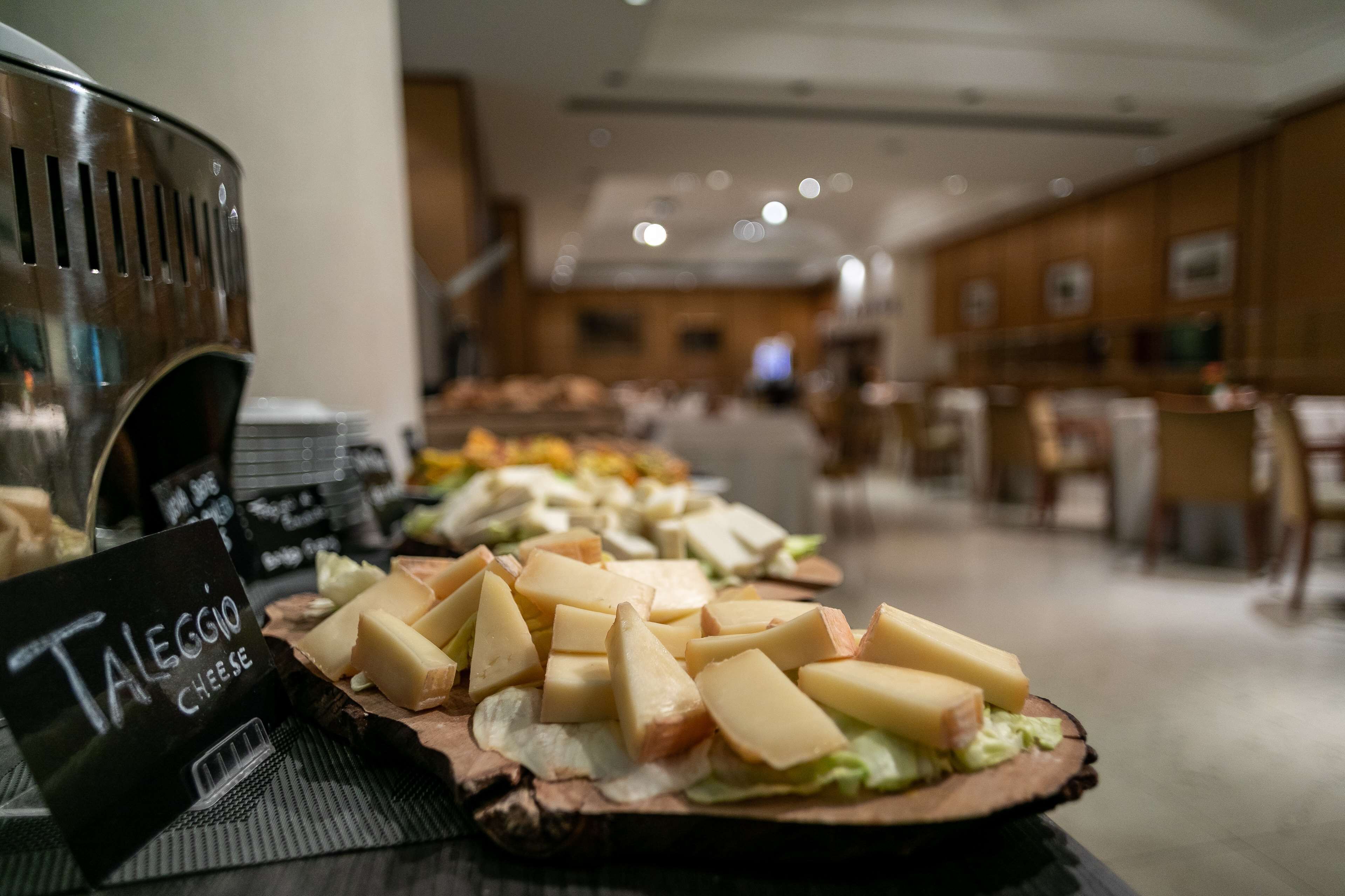Una mesa de buffet con varios quesos y un cartel que indica 'Taleggio Cheese'.