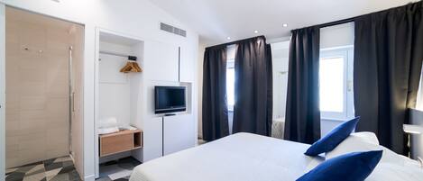 Habitación de hotel con cama, televisión, armario y ducha.