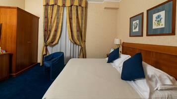 Een hotelkamer met een groot bed, een houten garderobe, een bureau en een stoel.