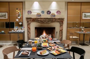 Una zona pranzo con camino, un tavolo apparecchiato per la colazione e diversi oggetti decorativi alle pareti.