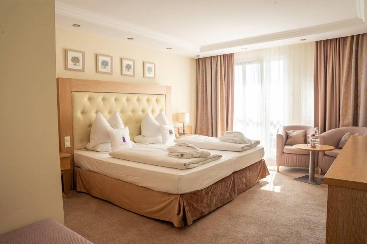A hotel room with a large bed, a sitting area, and a view of the outdoors.
