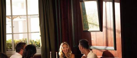 A dining area with a table set for four people, a window with curtains, and a framed picture on the wall.
