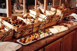 A buffet with various food items including pretzels, bread, and a fruit platter.