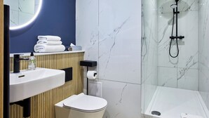 A modern bathroom with a vanity, toilet, and walk-in shower. - Handel's Hotel (Dublin)