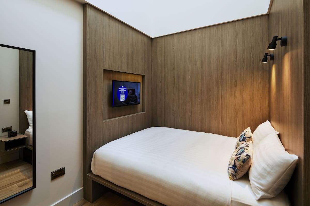 Un dormitorio moderno con una cama grande, un televisor empotrado y una pared de acento de madera.