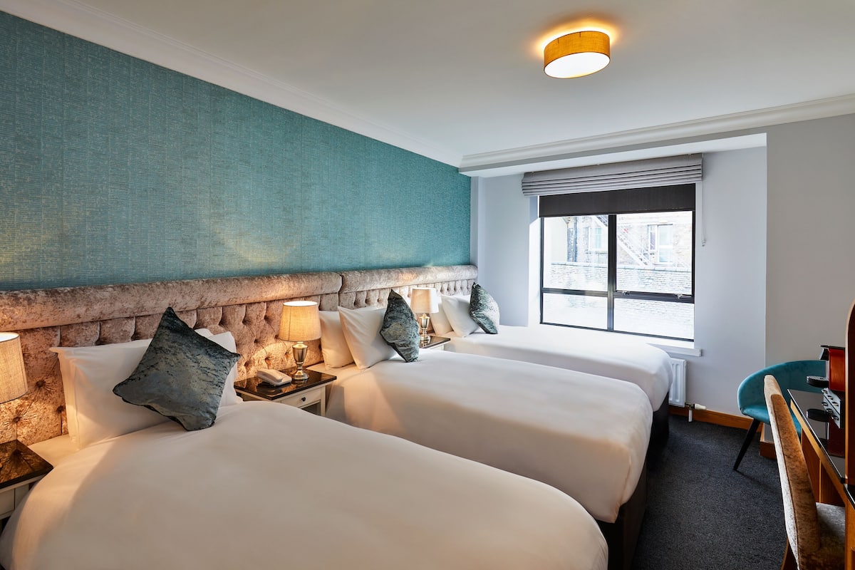 Una habitación de hotel con dos camas, un ventanal grande y un escritorio.