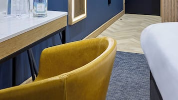 Relax in a stylish room with a neatly made bed, wooden-framed mirror, and a small desk.