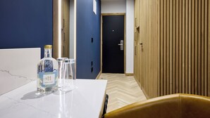 A hotel room with a white marble table, a bottle of hand sanitizer, and a glass. There is a wooden door and a beige wall in the background. - Handel's Hotel (Dublin)