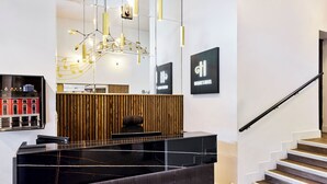 A reception desk with a modern design, a staircase with wooden steps, and a wall-mounted sign indicating the hotel name. - Handel's Hotel (Dublin)