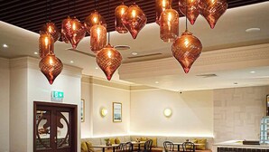 A restaurant with multiple seating areas, including booths and tables. There are decorative hanging lights above the tables.