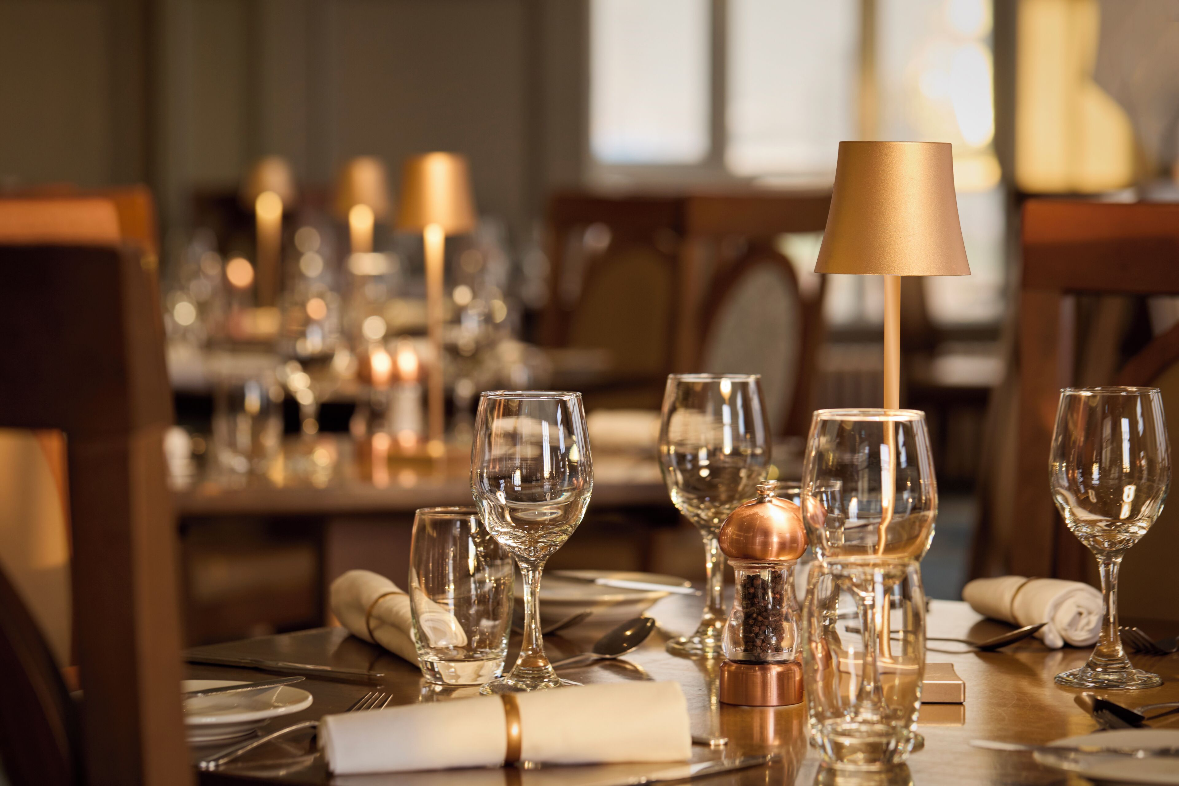 A dining table set with multiple wine glasses, a salt and pepper shaker, and a lamp.