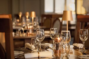 Una mesa de comedor dispuesta con varias copas de vino, un salero y pimentero, y una lámpara.