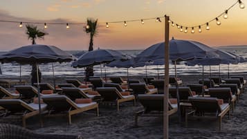 Een privéstrand, ligstoelen aan het strand, parasols, strandlakens