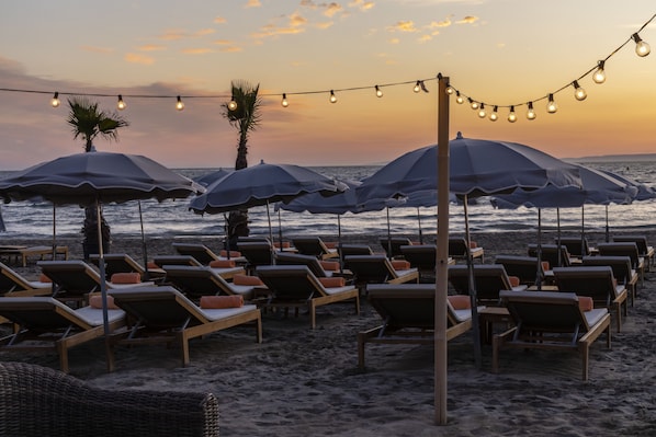 Een privéstrand, ligstoelen aan het strand, parasols, strandlakens