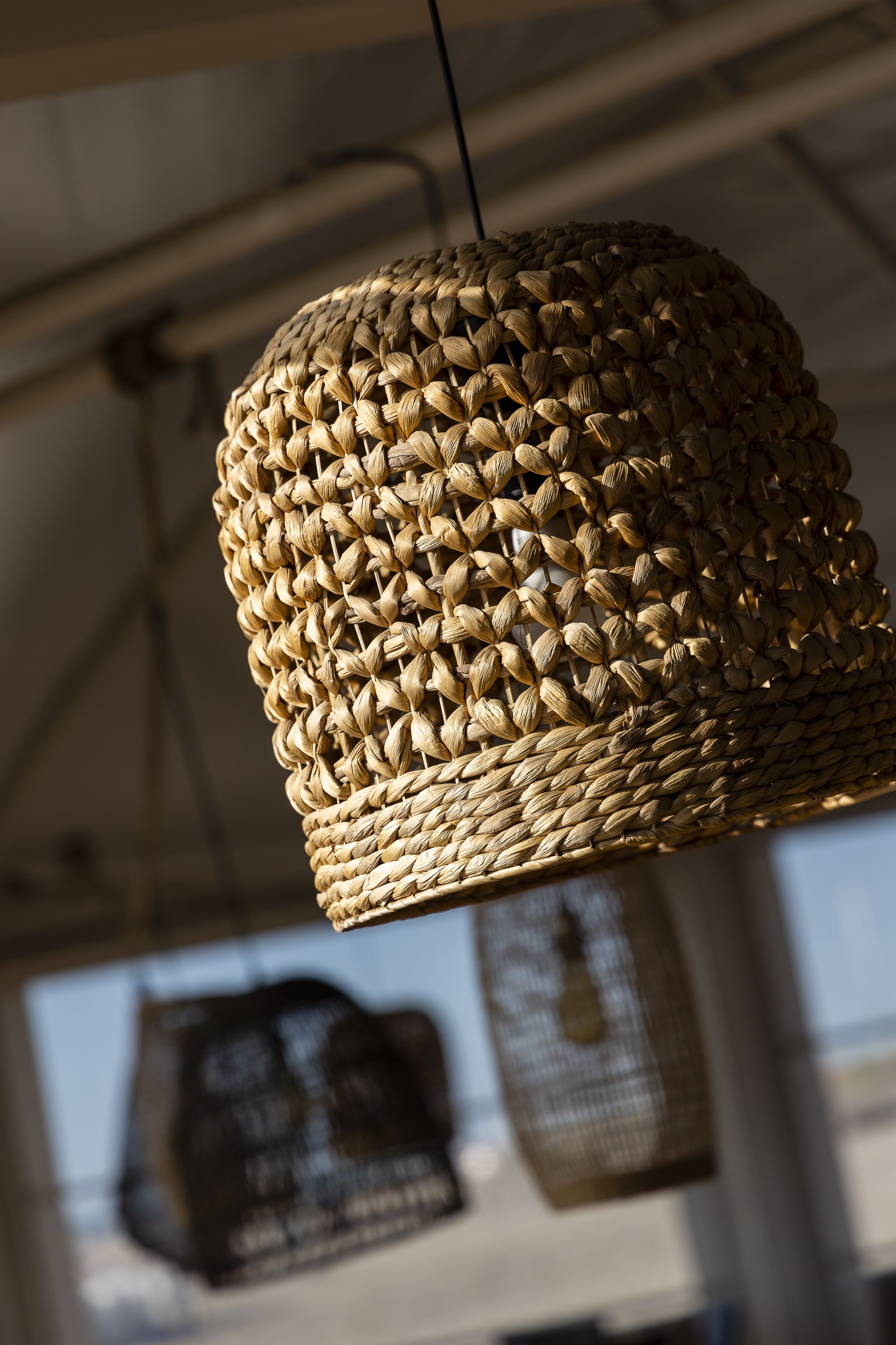 A woven hanging light fixture with a cylindrical shape.