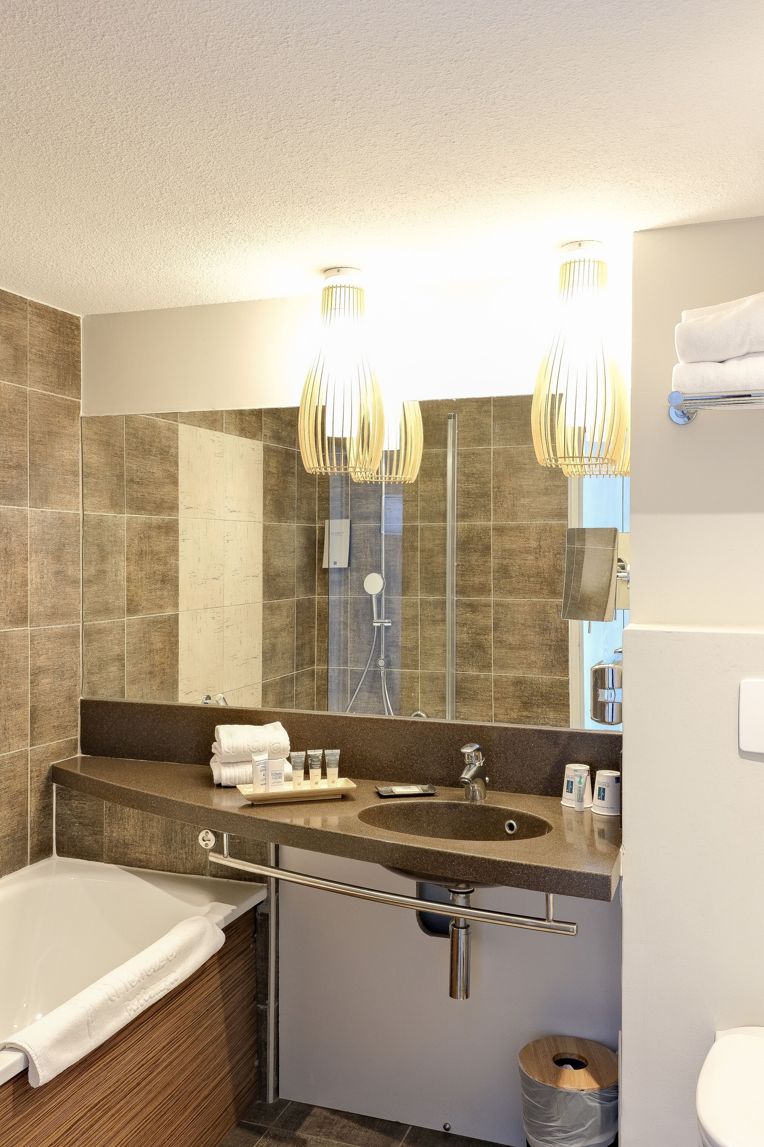 Un baño moderno con un espejo grande, dos lavamanos, una bañera y un inodoro.