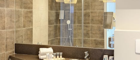 A modern bathroom with a large mirror, two sinks, a bathtub, and a toilet.